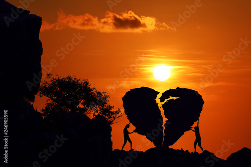 Couple on the broken heart shape rock on the mountain with red sky sunset.
