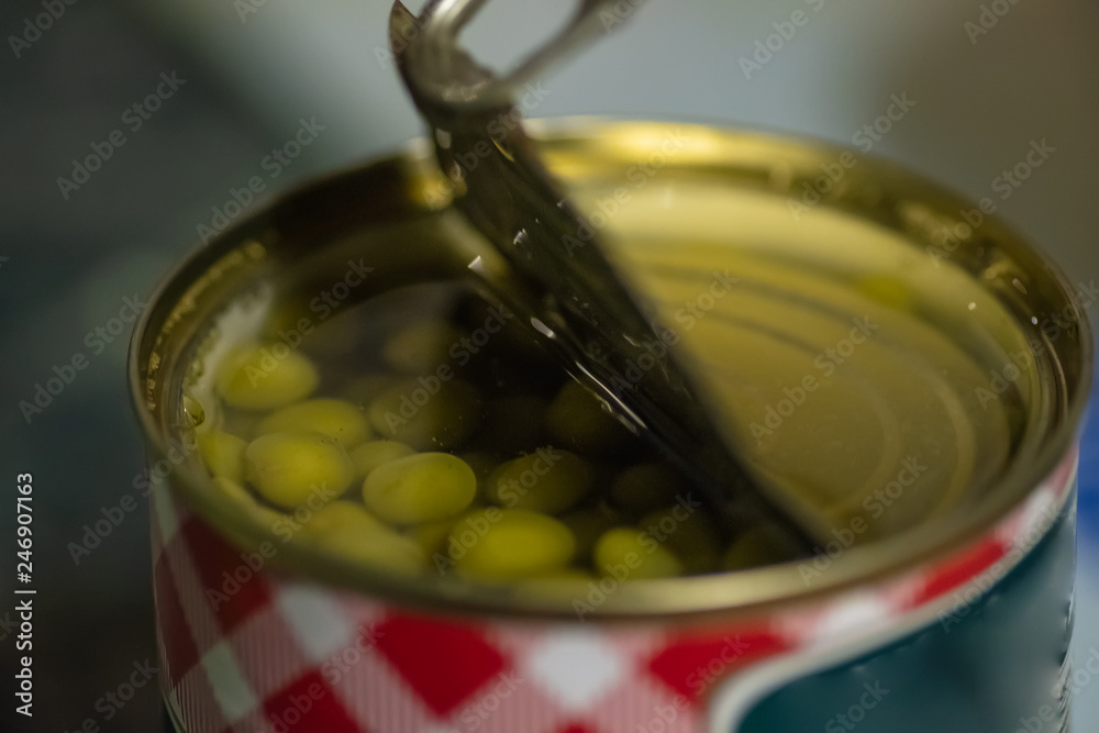 Open tin can of green peas closeup shallow DOF