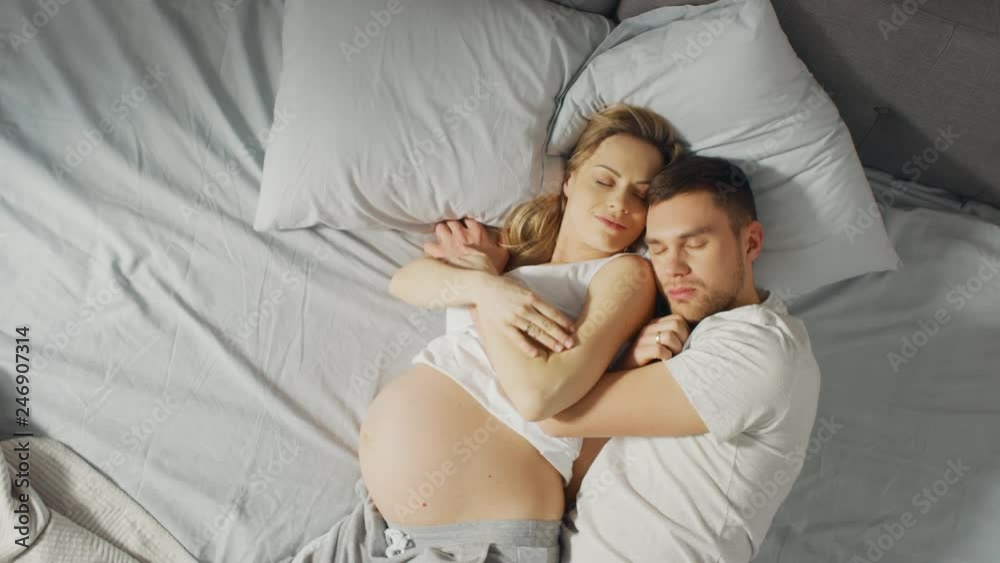 Happy Young Couple Sleeping Together in the Bed, Sweet Loving Young People Holding Each other while Sleeping. Beautiful Woman is Pregnant, Loving Partner Supports Her By Being there For Her. Happy Young Couple Sleeping Together in the Bed, Sweet Loving Young People Holding Each other while Sleeping. Beautiful Woman is Pregnant, Loving Partner Supports Her By Being there For Her.