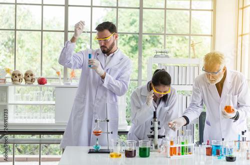 Group of scientist working putting medical chemicals sample in test tube at laboratory together