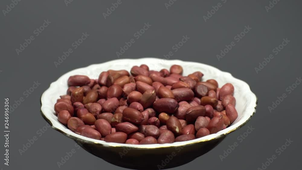 Raw unpeeled peanuts. Rotation. Snack closeup. Peanuts in a bowl. Selective focus. grey background. Studio shot. Healthy food concept. Raw unpeeled peanuts. Rotation. Snack closeup. Peanuts in a bowl. Selective focus. grey background. Studio shot. Healthy food concept.