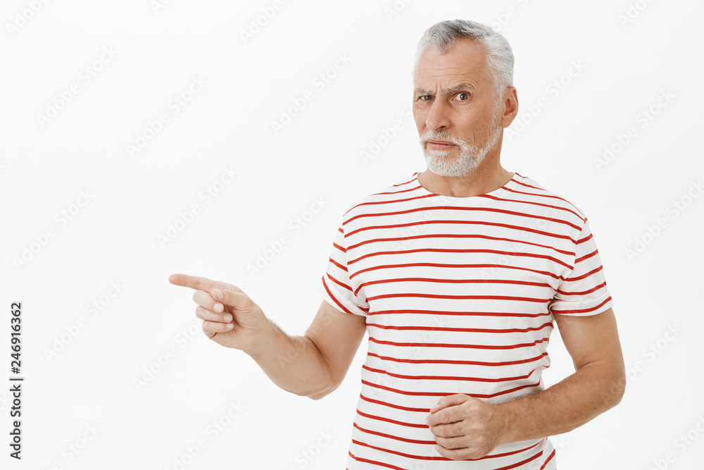 Retirement, age and people concept. Portrait of hesitant doubtful handsome old  male with white beard in striped t-shirt raising eyebrow questioned  pointing left at object being unsure over gray wall Stock Photo |