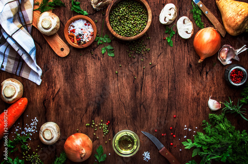 Ingredients for cooking green lentils with mushrooms and vegetables, spices and herbs, vintage wooden kitchen table background, place for text. Vegan or vegetarian food, clean food concept