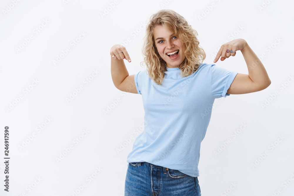 Hey come on click down. Portrait of optimistic and charismatic stylish young 20s european female with short blond curly hair and blue eyes smiling excited as pointing down at awesome sale Hey come on click down. Portrait of optimistic and charismatic stylish young 20s european female with short blond curly hair and blue eyes smiling excited as pointing down at awesome sale