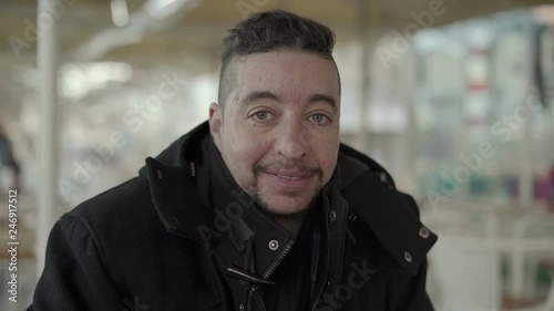 Cheerful middle aged man smiling at camera. Portrait of happy handsome man in black coat looking at camera while sitting in outdoor cafe, handheld shot. Facial expression concept photo