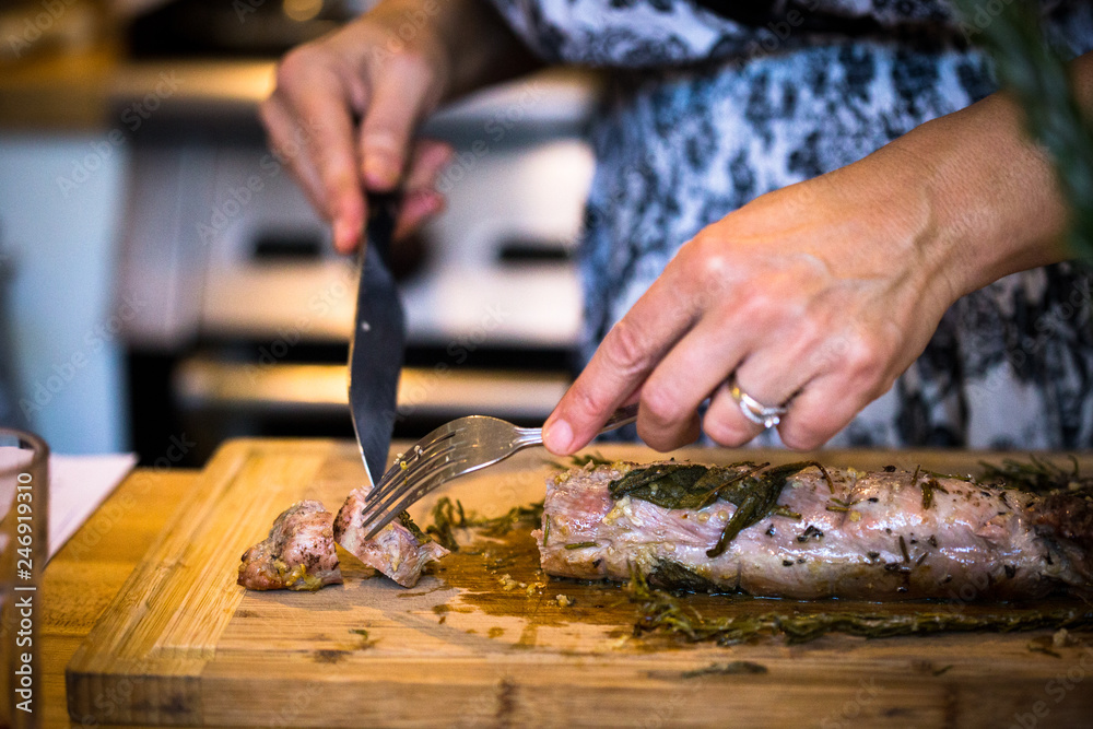 Cutting roasted pork wrapped in herbs