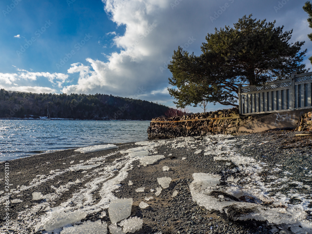 winter landscape with ice on rocky shore and clouds