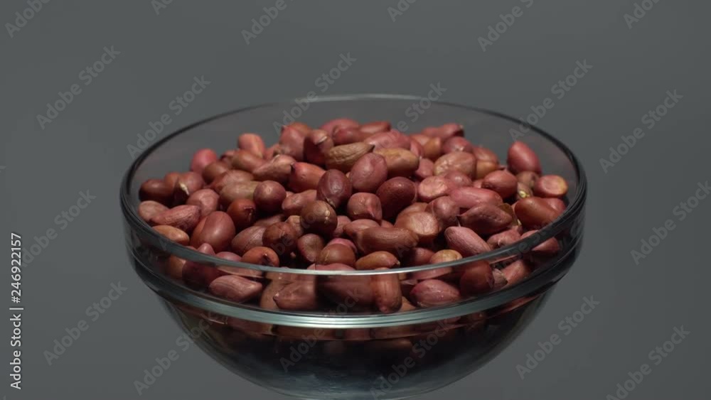 Raw unpeeled peanuts. Rotation. Snack closeup. Peanuts in a bowl. Selective focus. grey background. Studio shot. Healthy food concept. Raw unpeeled peanuts. Rotation. Snack closeup. Peanuts in a bowl. Selective focus. grey background. Studio shot. Healthy food concept.