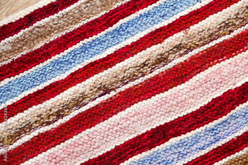 different colored stripes on the knitted fabric surface. background close-up of textiles retro rugs or rugs. the texture of the fabric is a combination with the geometry of the lines. handmade product different colored stripes on the knitted fabric surface. background close-up of textiles retro rugs or rugs. the texture of the fabric is a combination with the geometry of the lines. handmade product