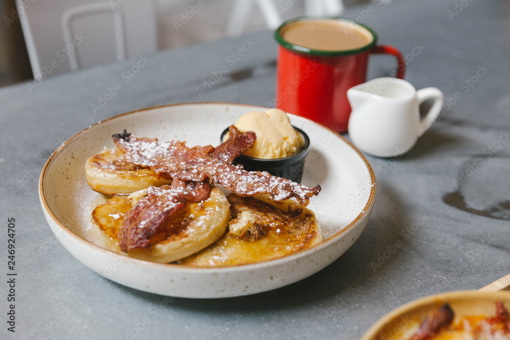 Pancakes with butter and maple syrup with Crispy Bacon and Vanilla Ice Cream. Topping with icing. Served with hot coffee and milk. Pancakes with butter and maple syrup with Crispy Bacon and Vanilla Ice Cream. Topping with icing. Served with hot coffee and milk.