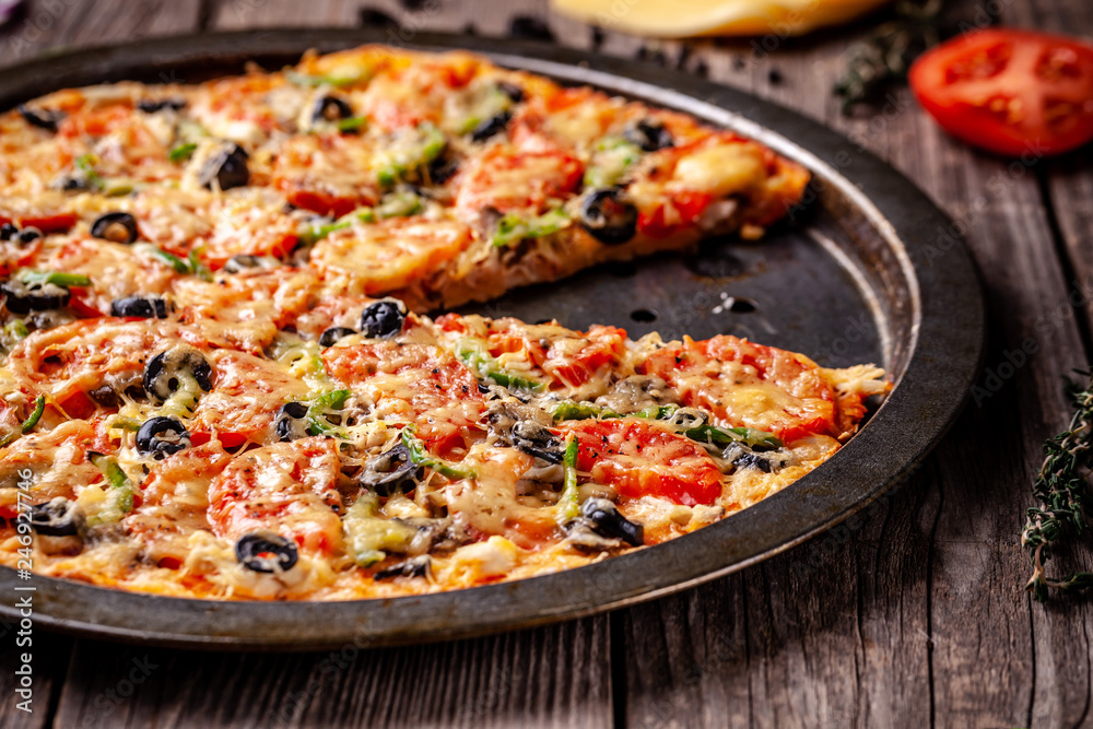Concept of Italian cuisine, Homemade Italian pizza with salami sausage, tomatoes, with black olives and cheese on a wooden background. copy space Concept of Italian cuisine, Homemade Italian pizza with salami sausage, tomatoes, with black olives and cheese on a wooden background. copy space