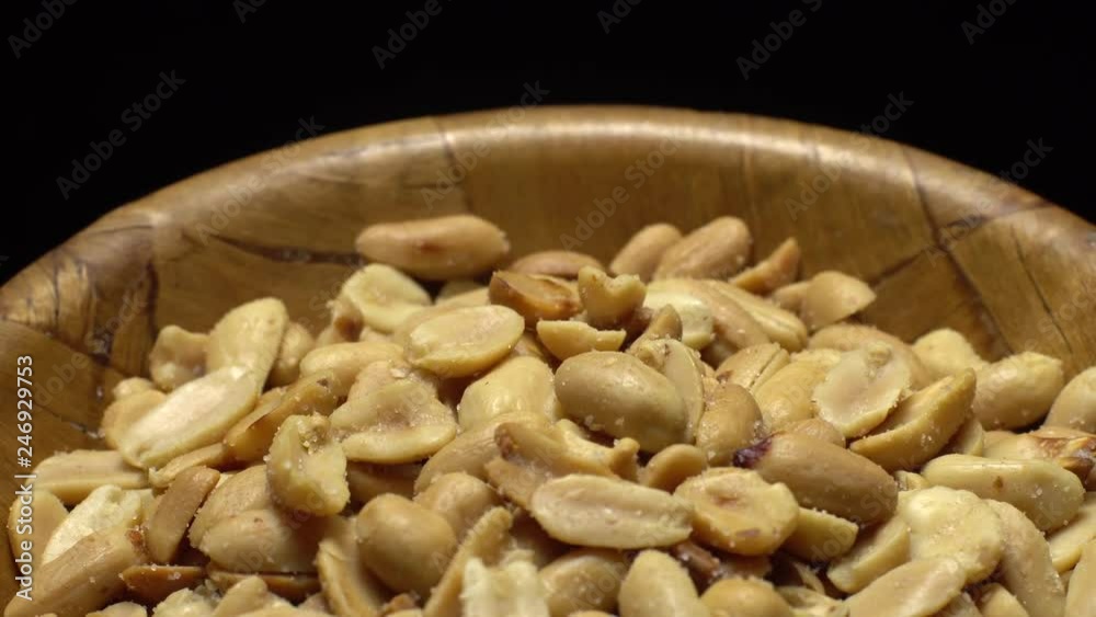 Peanuts. Peeled peanuts fried with salt.  Rotation. Snack closeup.   Peanuts in a bowl. Selective focus. black background. Studio shot.