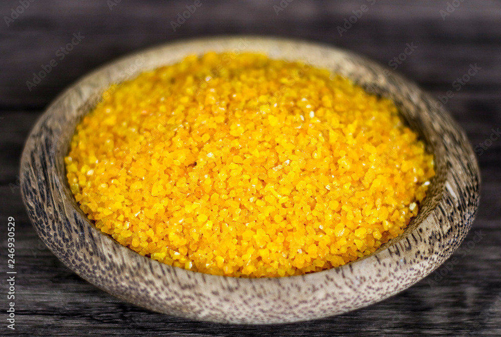 Yellow corn grits on wood background. 