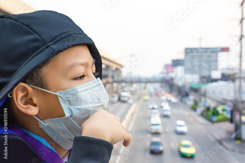 Asean Boys wear a mask to prevent dust Background Blurry car driving on the road and sky train stations.