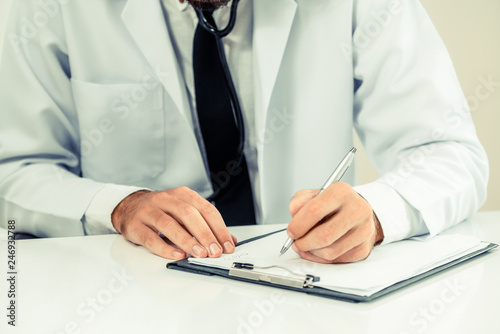 Doctor in hospital working and writing on paperwork. Healthcare and medical service concept. photo