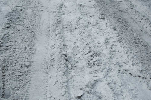 Covered with dirty snow road for movement of cars. Footprints from car in snow as abstract background.