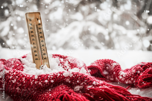 thermometer with sub zero temperature sticks out in a snowdrift wrapped red scarf photo