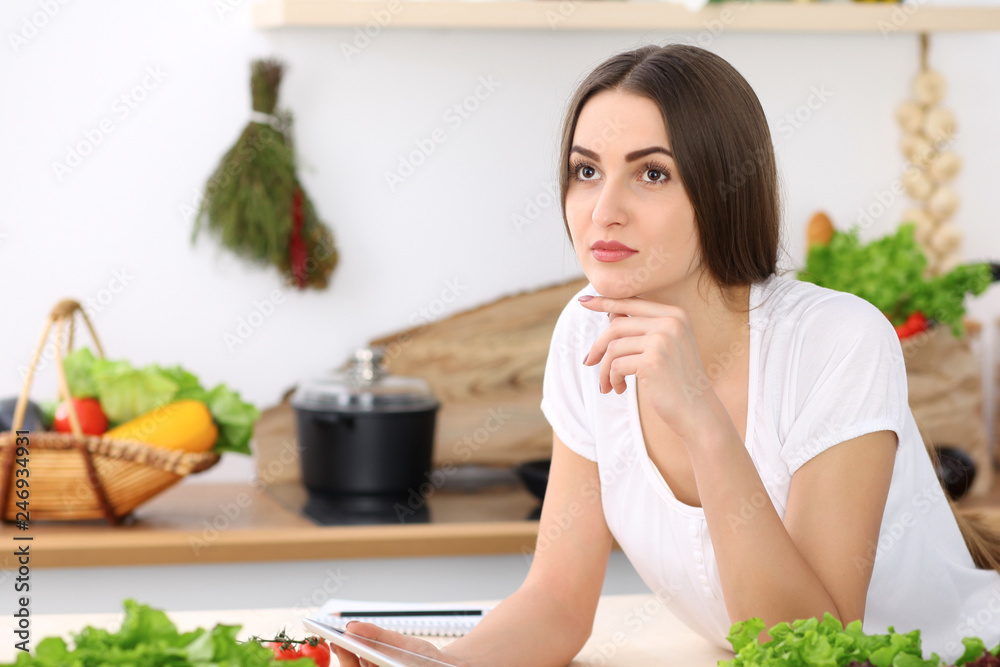 Beautiful Hispanic woman cooking while using tablet computer in kitchen or making online shopping by touchpad and credit card. Housewife found new recipe for dinner Beautiful Hispanic woman cooking while using tablet computer in kitchen or making online shopping by touchpad and credit card. Housewife found new recipe for dinner