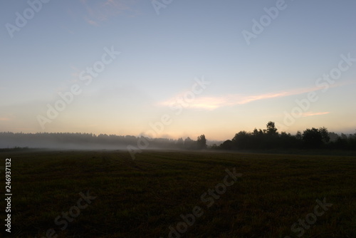 Sunlight of dawn in the blue sky above a field in the morning mist early morning.