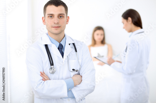 Medicine doctor standing and smiling on the background with patient in the bed