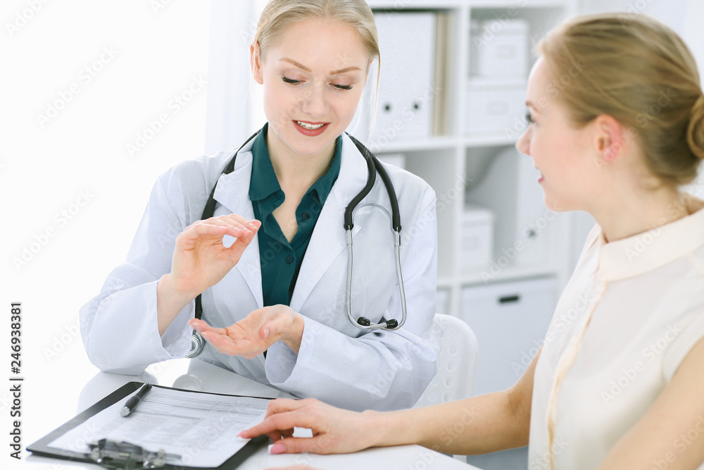 Doctor and patient talking in hospital office while sitting at the desk. Health care and client service in medicine Doctor and patient talking in hospital office while sitting at the desk. Health care and client service in medicine