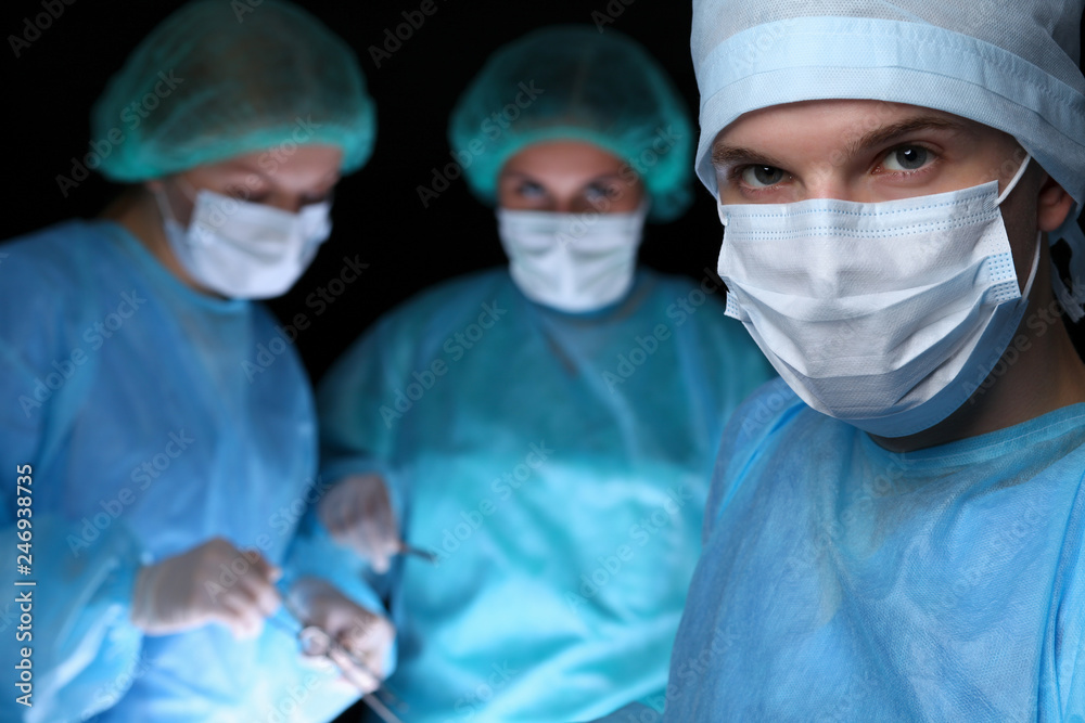 Closeup of surgeons performing operation. Focus on male doctor. Medicine, surgery and emergency help concepts Closeup of surgeons performing operation. Focus on male doctor. Medicine, surgery and emergency help concepts