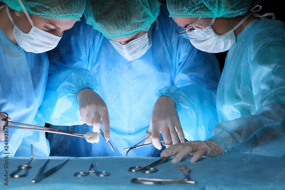 Group of surgeons in masks performing operation. Medicine, surgery and emergency help concepts Group of surgeons in masks performing operation. Medicine, surgery and emergency help concepts