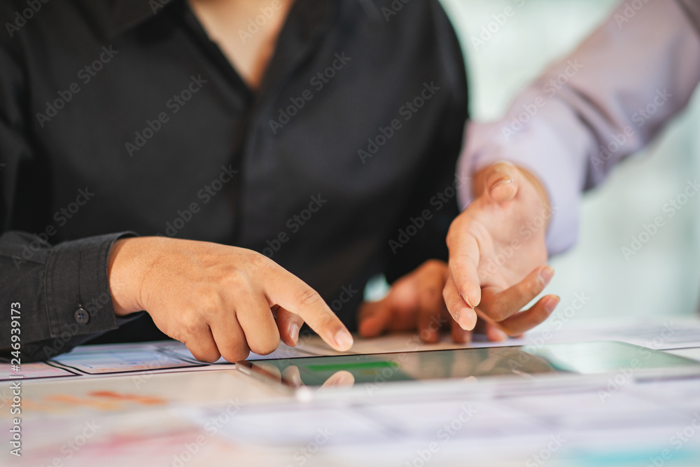 Business partners use tablet discussing documents and ideas at meeting.