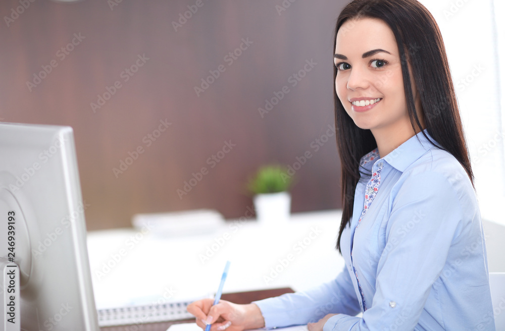 Young brunette business woman looks like a student girl working in office. Hispanic or latin american girl happy at work and too busy Young brunette business woman looks like a student girl working in office. Hispanic or latin american girl happy at work and too busy