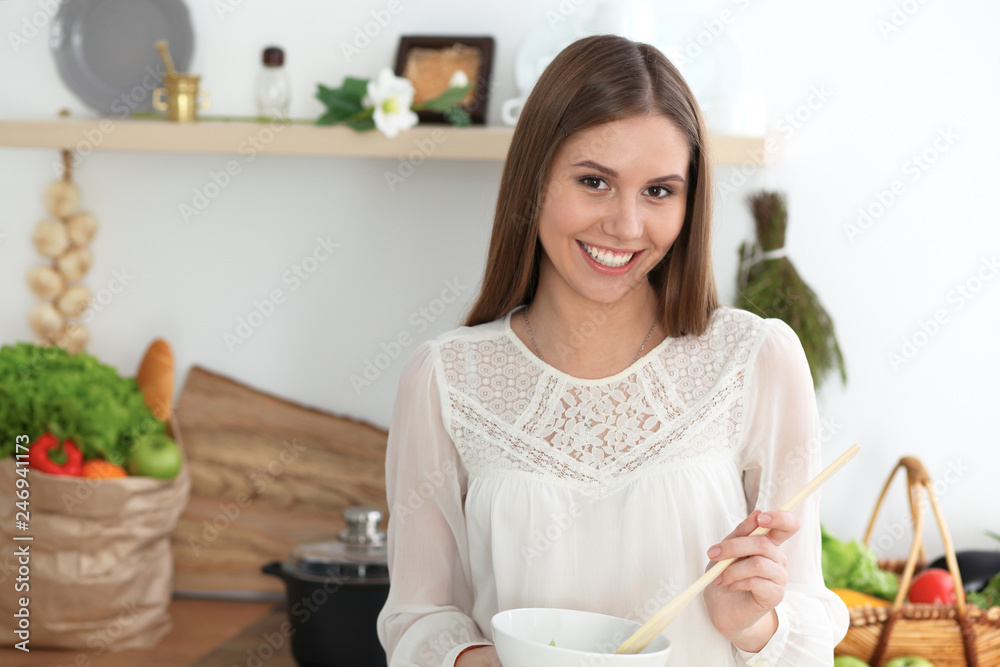 Young happy woman cooking in the kitchen. Healthy meal, lifestyle and culinary concepts. Good morning begins with fresh salad