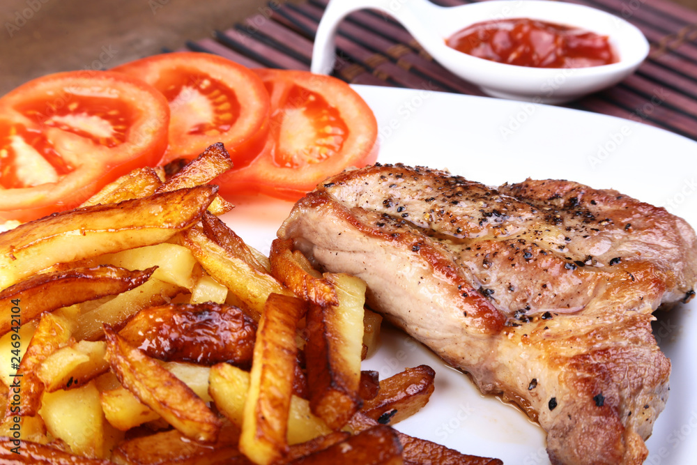 Grilled free-range beef steak with potato free, fresh tomatoes and sauce on a brown stone background Grilled free-range beef steak with potato free, fresh tomatoes and sauce on a brown stone background