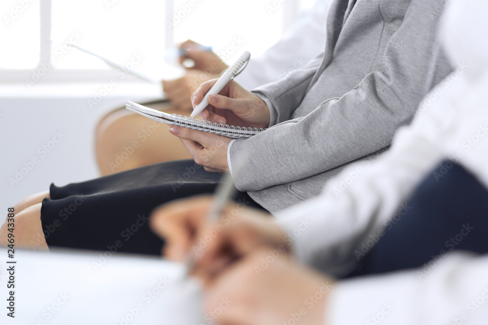 Business people taking part at conference or training at office, close-up. Women sitting on chairs and making notes like at queue or meeting Business people taking part at conference or training at office, close-up. Women sitting on chairs and making notes like at queue or meeting