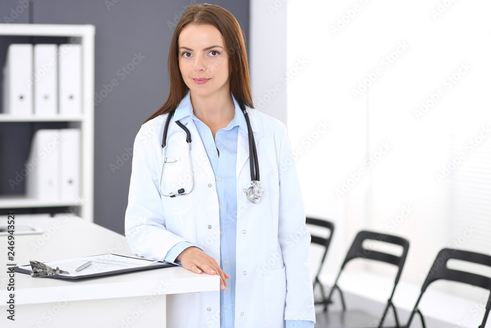 Doctor woman at work. Portrait of female physician standing near reception desk at clinic or emergency hospital. Medicine and healthcare concept Doctor woman at work. Portrait of female physician standing near reception desk at clinic or emergency hospital. Medicine and healthcare concept