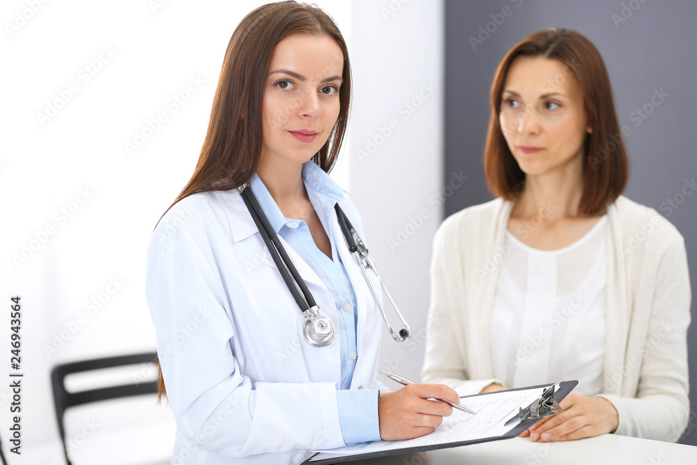 Doctor and patient discussing something while standing near reception desk in emergency hospital. Physician at work in clinic. Medicine and health care concept Doctor and patient discussing something while standing near reception desk in emergency hospital. Physician at work in clinic. Medicine and health care concept