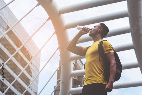 Yellow sporty guy is drinking water in hot day outdoor