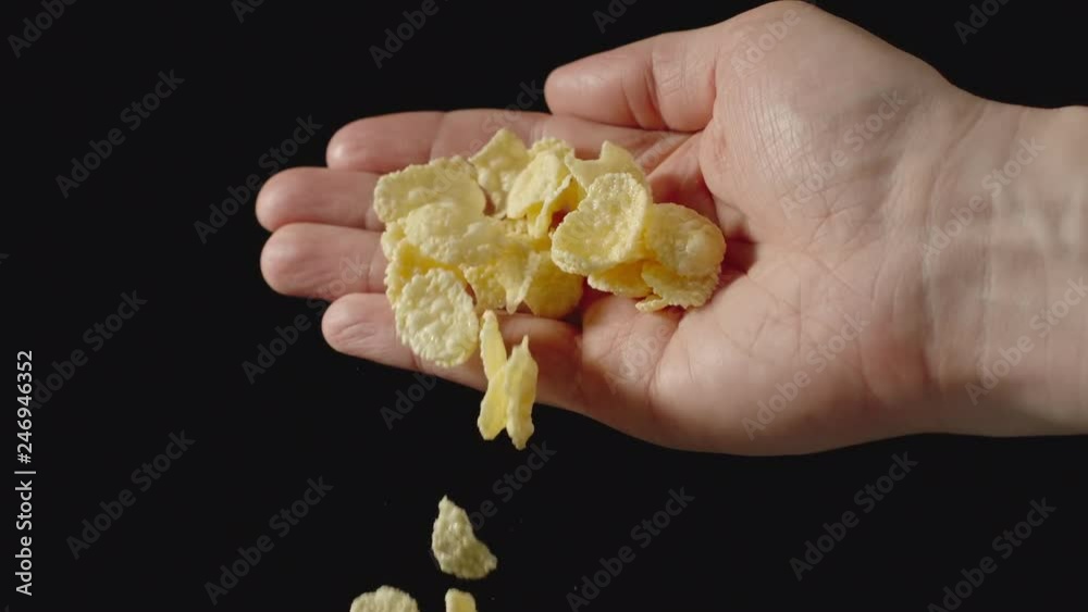 SLOW MOTION: Yellow cornflakes fall from man's palm - Front view SLOW MOTION: Yellow cornflakes fall from man's palm - Front view