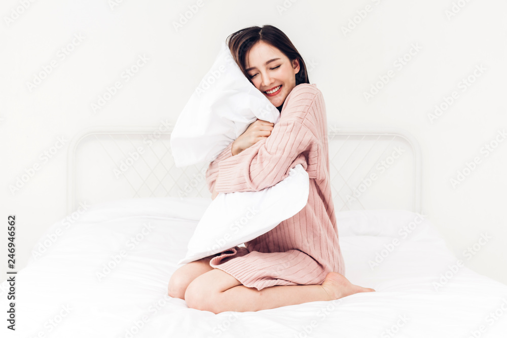 Beautiful woman smiling to camera and relaxing with pillow on the bed in her room at home Beautiful woman smiling to camera and relaxing with pillow on the bed in her room at home