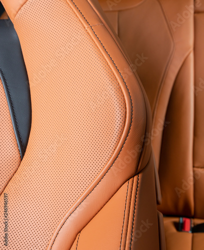 Part of red leather car seat with the unfocused car interior on the background © gargantiopa