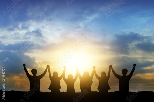 Silhouette image of happy teamwork join hands together up to the beautiful sky, successful business from good partnership and colleagues.