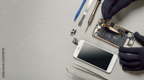 Technician or engineer disassembling components broken smartphone and take off logic board for repair or replace new smartphone logic board on desk  photo