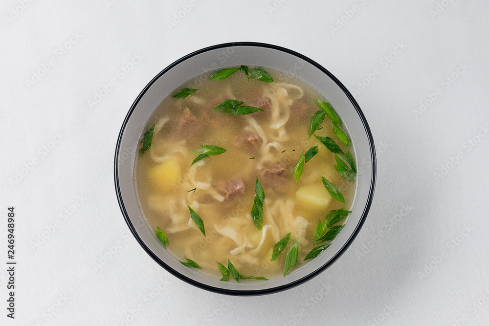 meat soup with homemade noodles, potatoes and fresh green onion on white background meat soup with homemade noodles, potatoes and fresh green onion on white background