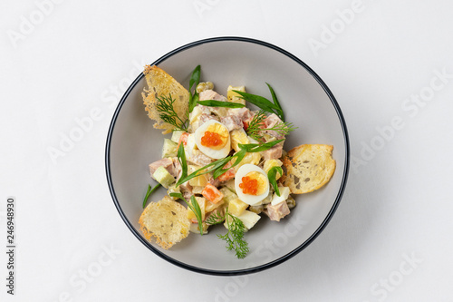 meat salad with sliced ​​quail eggs, caviar and fresh green onions, decorated with sliced ​​dried bread. Top view