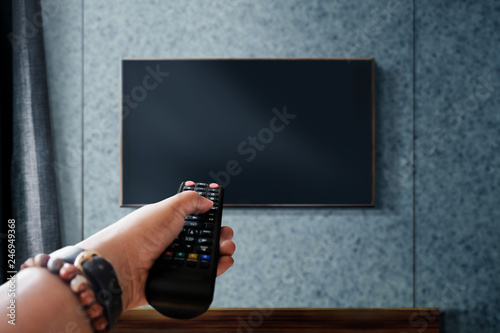 Watching Television Concept. Hand holding TV's Remote to Control or Changing Channel. Relaxation in Modern Living Room. Focus on Remote photo