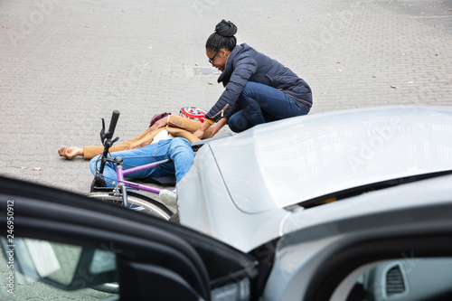 Woman Looking At Unconscious Male Cyclist Lying On Street