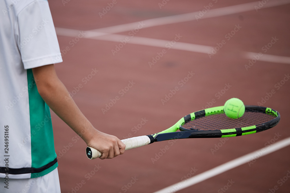 Close-up of male hand holding balancing tennis ball on racket. Professional tennis player starting set.