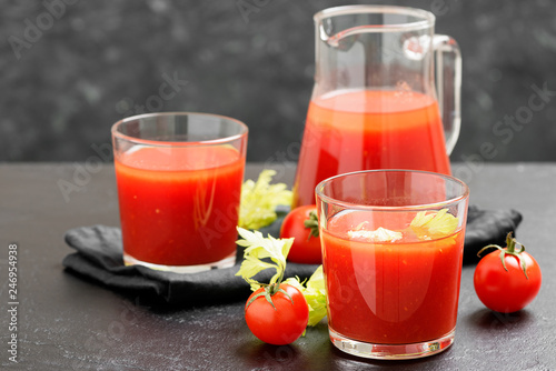 Tomato juice in glass with celery, cherry tomato  on dark background.