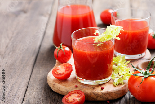 Tomato juice in glass with celery, cherry tomato on dark background.
