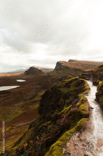 Hiking path at Quiraing on a moody cloudy autumn day with orange vegetation and panorama view of Skye (Isle of Skye, Scotland, Europe)