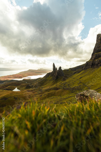 Old Man of Storr with grass foreground and the sun bursting through dramatic clouds during autumn (Isle of Skye, Scotland, United Kingdom)