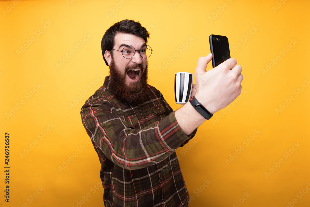 Portrait of Energized bearded man taking selfie while drinking coffee Portrait of Energized bearded man taking selfie while drinking coffee